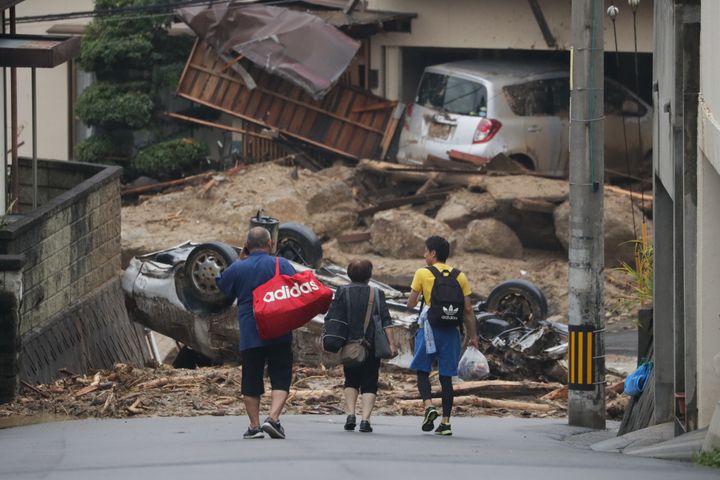 土砂や流木が散乱し、車両が転がった住宅地を歩く住民ら＝2018年7月8日、広島市安芸区