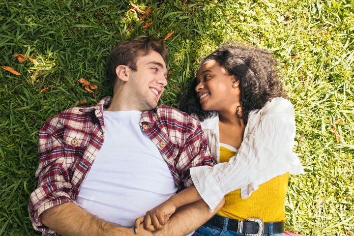 Overhead view of a young interracial couple lying on the grass in the park