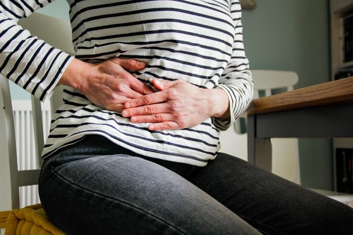 Woman clutches her stomach in pain.