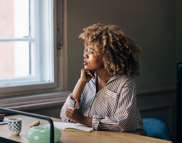 A pensive African-American entrepreneur contemplating while sitting at the desk.