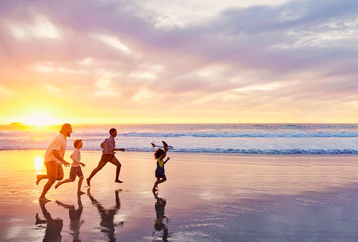 Woman friends taking off their clothes and throwing while running towards  the ocean. Excited women going for swimming in the sea on a summer day.  stock photo