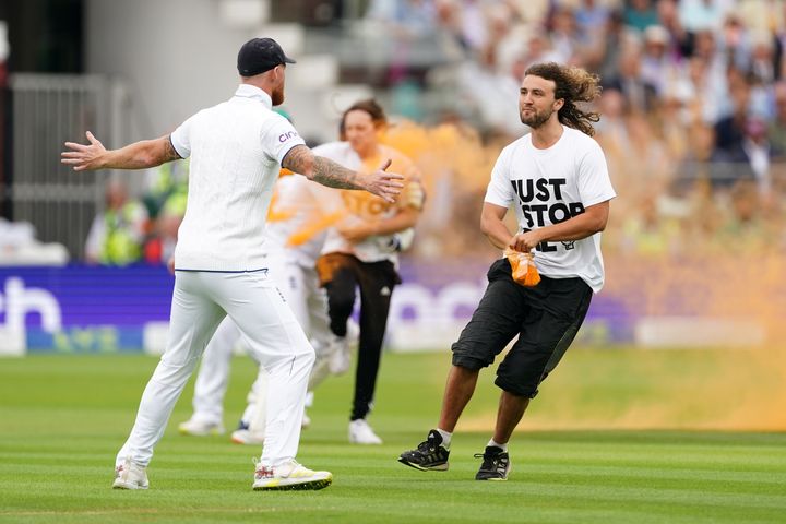 England's Ben Stokes holds out his arms to stop a Just Stop Oil protester.