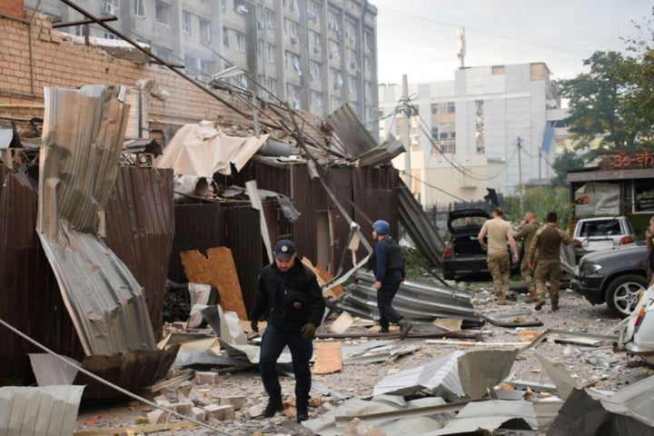 In this photo provided by the National Police of Ukraine, a police officer and a rescue worker walk in front of a restaurant RIA Pizza destroyed by a Russian attack in Kramatorsk, Ukraine, on June 27, 2023.