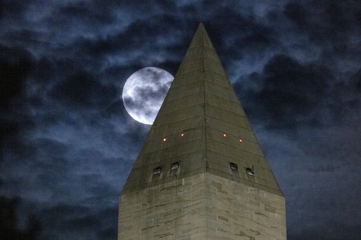 A supermoon partially obscured by clouds as it passes behind the Washington Monument on August 11, 2022 in Washington, DC.