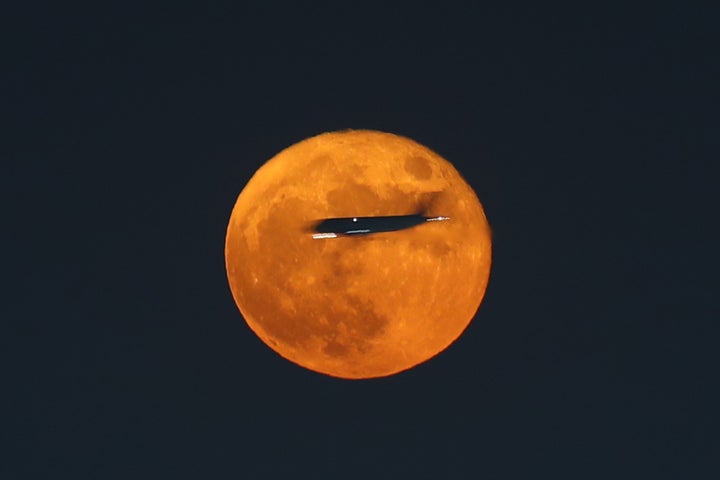 An airplane is silhouetted against a super moon over Cairo, Egypt, on August 12, 2022.