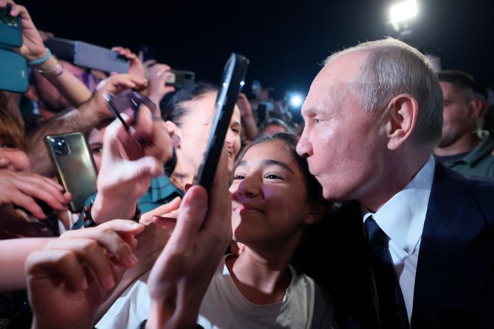 若い女性の支持者と記念写真を撮る際に頭にキスするプーチン大統領 (Gavriil Grigorov, Sputnik, Kremlin Pool Photo via AP)