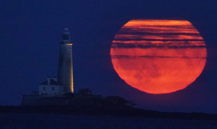 The Full Buck supermoon rises over St Mary's Lighthouse in Whitley Bay on the North East coast of England.