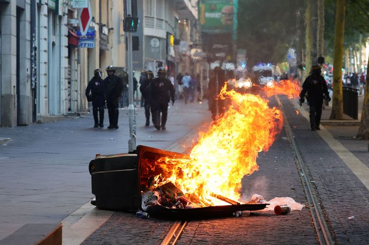 French riot police officers stand guard behind a burnt trash bin during a demonstration against police in Marseille, southern France on July 1, 2023.