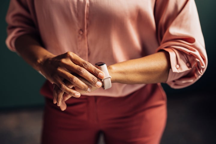 An unrecognizable African-American entrepreneur looking at her smartwatch while waiting for somebody who is late.