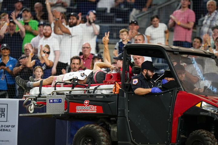 Pete Stendel gestures to the crowd as he is carted off the field during the fifth inning of the Orioles' baseball game against the New York Yankees.