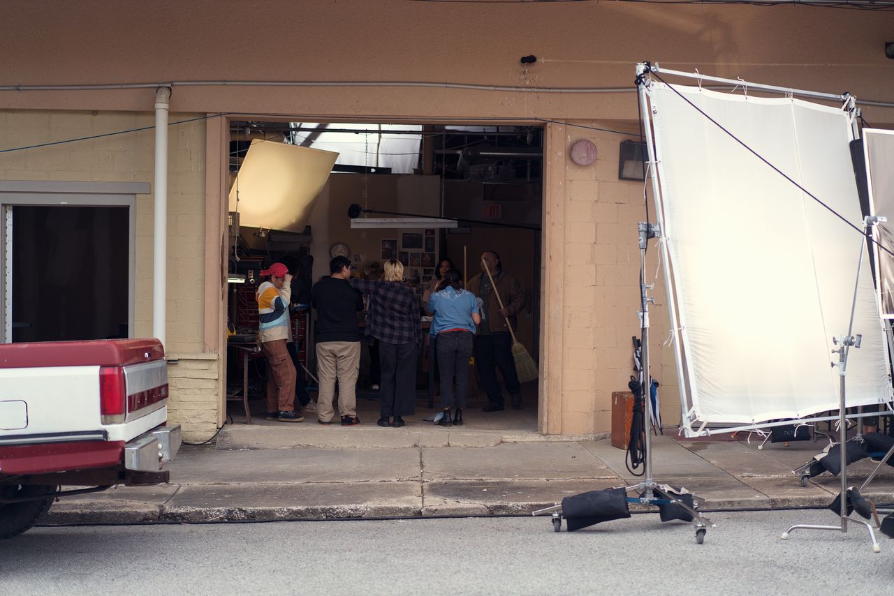 The young actors stand at the edge of the set for Leon’s office, lit from behind.