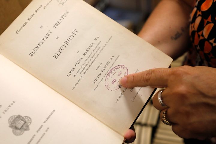 New Bedford Public Library Director Olivia Melo points to a stamp dating to 1882, when the New Bedford library system acquired the book.