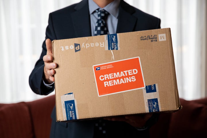 Funeral director Archer Harmon poses for a portrait with a box of cremated human remains at Fairfax Memorial Funeral Home in Fairfax, Virginia, on March 1, 2021. The remains were those of a veteran and were to be sent to Arlington National Cemetery.