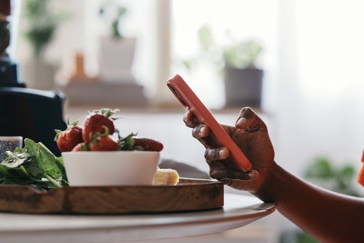 An anonymous African American woman using her smartphone to follow a recipe for a smoothie.