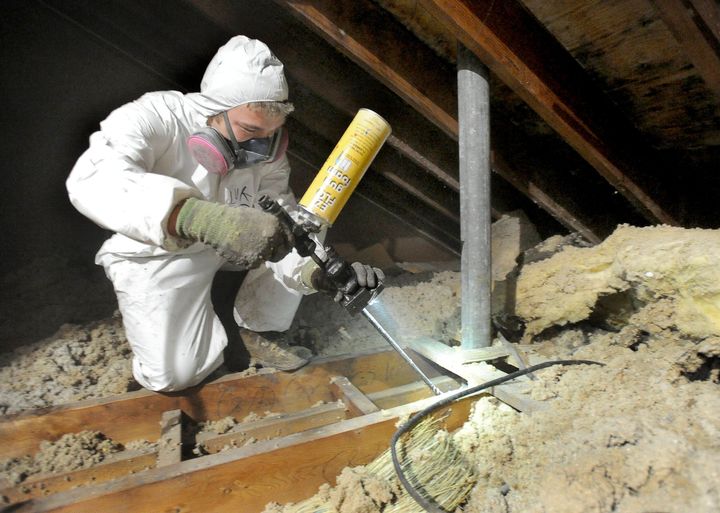 A home-performance technician sprays insulation in a home in Portland, Maine, as part of a weatherization effort. 
