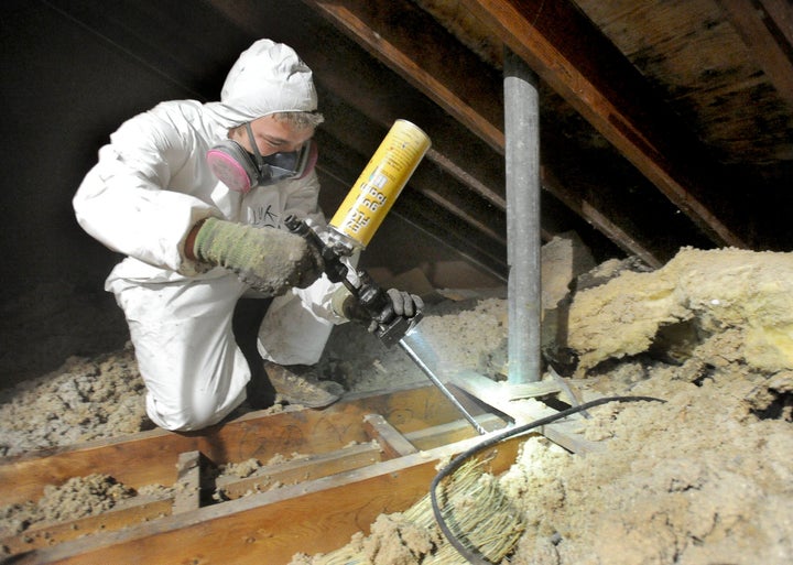 A home-performance technician sprays insulation in a home in Portland, Maine, as part of a weatherization effort.