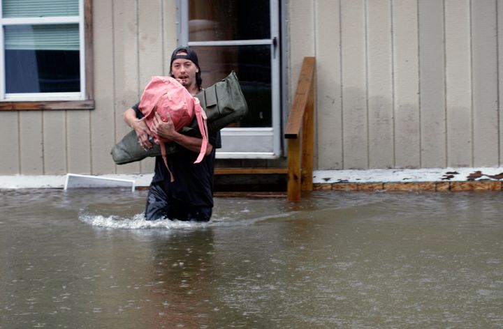 A man carries belongings through floodwaters from a home in Bridgewater, Vt., Monday, July 10, 2023.
