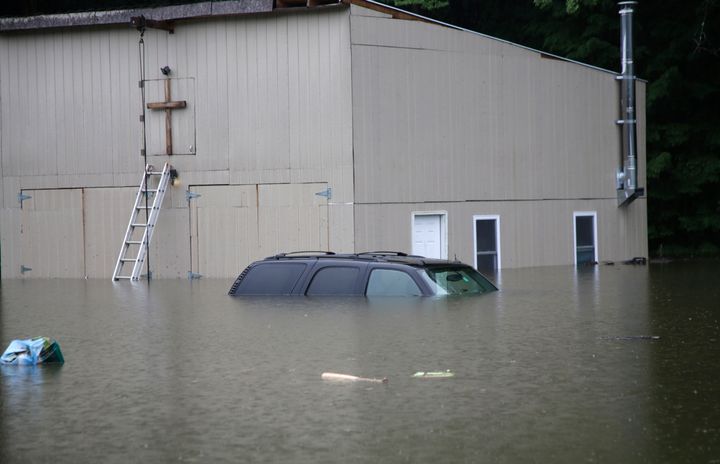 Floodwaters rise in Bridgewater, Vermont, on Monday, July 10, 2023, submerging parked vehicles and threatening homes near the Ottauquechee River. 