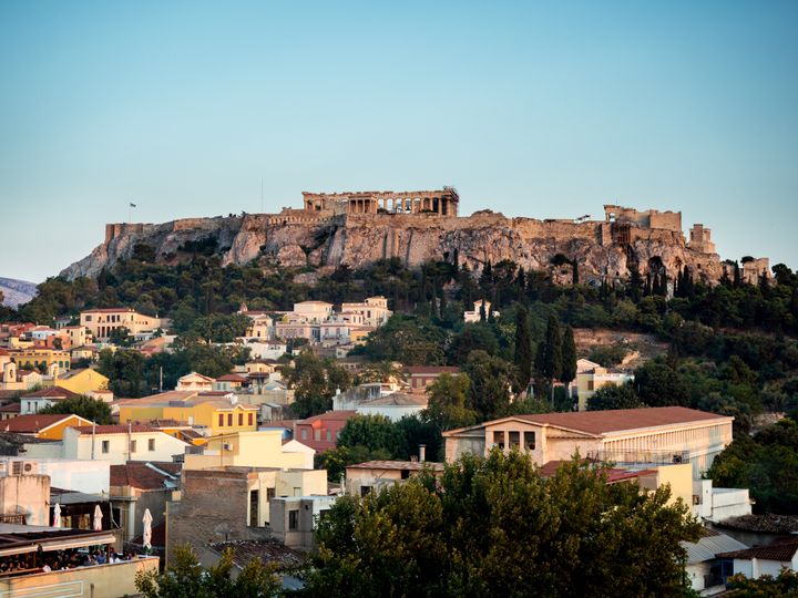 Sitting in a rooftop bar in athens at sunset looking across the skyline at the Acropolis and Parthenon