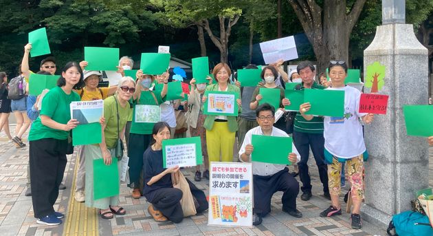 緑の紙を掲げて再開発に抗議する人たち