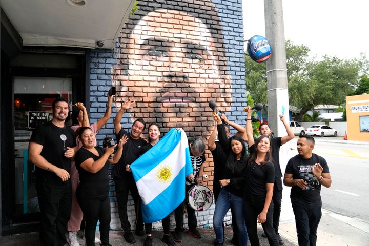 Staff at the Fiorito restaurant pose in front of a mural of Lionel Messi to celebrate his imminent arrival.