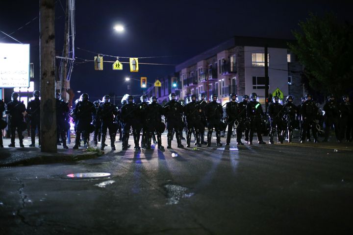 A line of Portland police officers stands with batons in hand during a protest at the Portland Police Association's union building on June 30, 2020.
