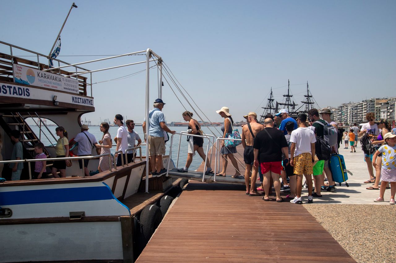 Κόσμος επιβιβάζεται σε καραβάκι στην Παραλία Θεσσαλονίκης για μια βουτιά στους Νέους Επιβάτες ή την Περαία 