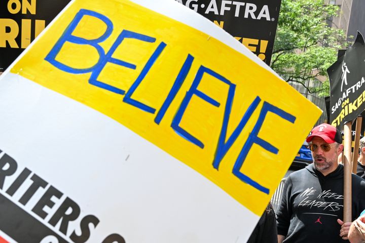 Actor Jason Sudeikis is seen behind a "believe" sign — a reference to "Ted Lasso" — while picketing NBC outside Rockefeller Center on Friday in New York City.