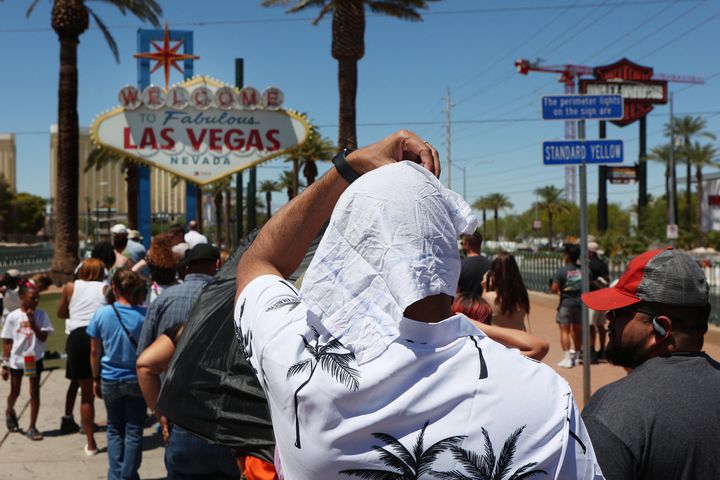 A man shields himself from the sun in front of the historic Welcome to Las Vegas Sign during a heat wave in Las Vegas, Nevada, on July 14, 2023.