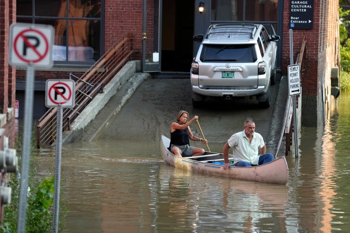 Jodi Kelly, left, practice manager at Stonecliff Veterinary Surgical Center, behind, and her husband, veterinarian Dan Kelly, use a canoe to retrieve surgical supplies from the flood-damaged center. 