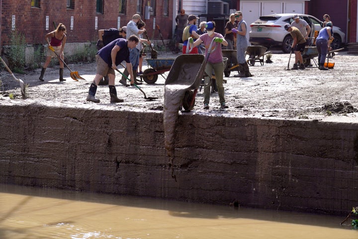 Volunteers clear a downtown parking lot on the banks of the Winooski River on July 12.