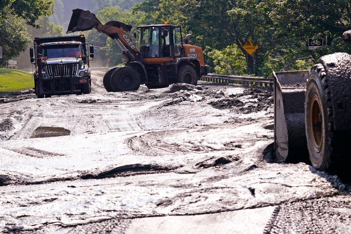 Buckets clear mud from a road in Montpelier on July 12. 