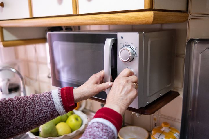 a old woman closing the microwave in her kitchen