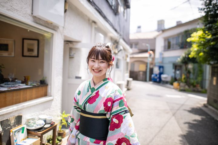 Happy young woman in yukata walking on old street