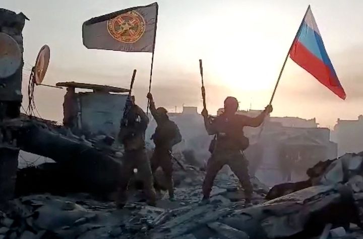 ウクライナ東部バフムトとされる場所でロシア国旗を掲げる民間軍事会社「ワグネル」戦闘員＝通信アプリに2023年5月20日に投稿された動画より
