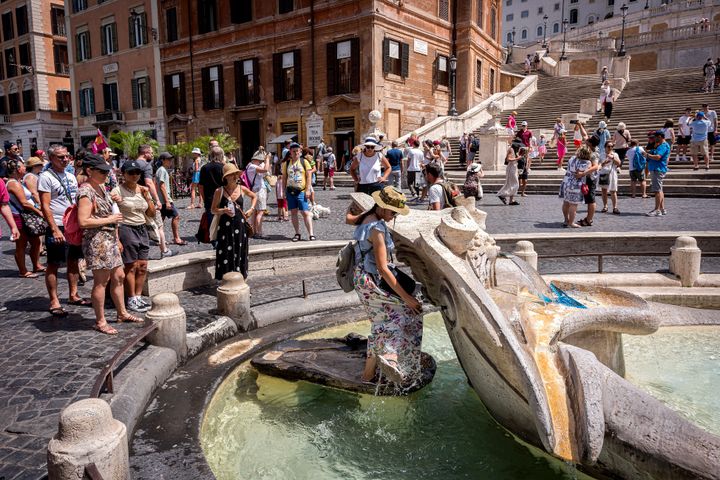 Τουρίστες περιμένουν στην ουρά για να ανακουφιστούν με λίγο νερό από το συντριβάνι «Μπαρκάτσα» στην Πιάτσα ντε Σπάνια, στη Ρώμη (17/7/2023). 