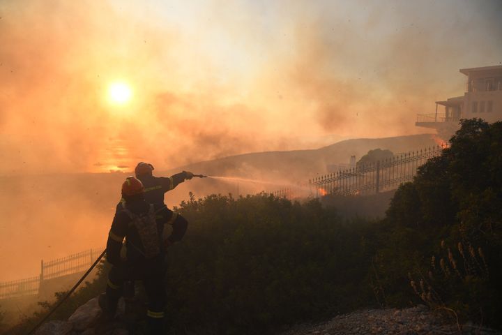 Firefighters extinguish a house burning during a wildfire in southeast Attica in Lagonisi, Greece on 17, July 2023.