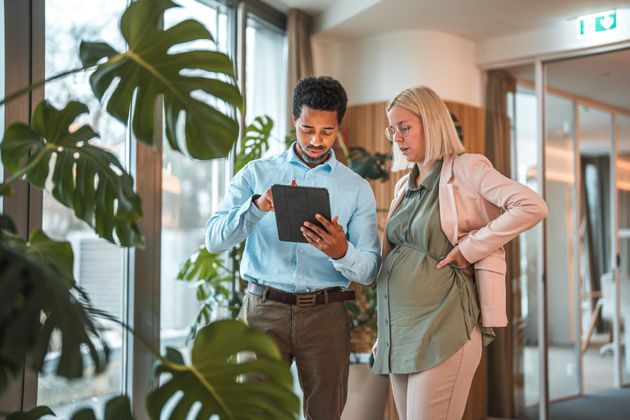 Pregnant woman and her manager check a report on a tablet.