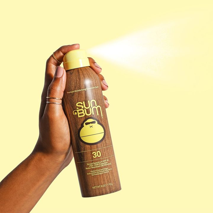 A hand spraying Sun Bum suntan lotion