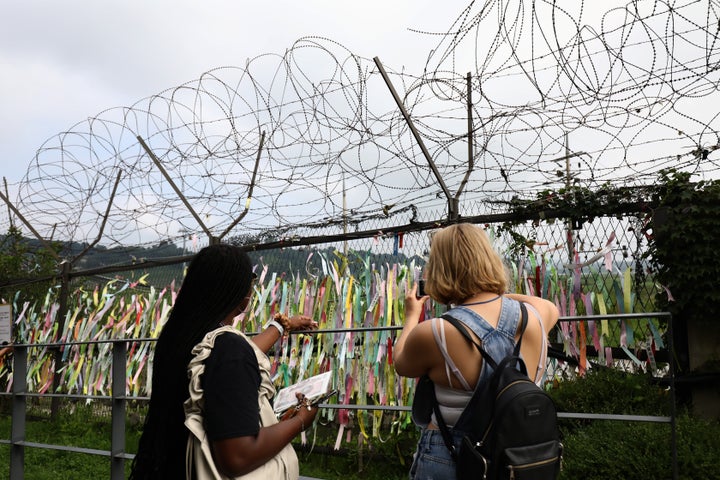 Tourists take pictures of prayer ribbons wishing for reunification of the two Koreas on the wire fence at the Imjingak Pavilion, near the demilitarized zone (DMZ) on July 19, 2023, in Paju, South Korea.