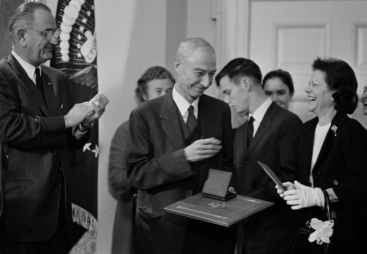 President Lyndon Johnson applauds as Oppenheimer turns over to his wife a check for $50,000 during White House ceremonies, Dec. 2, 1963. The check was part of the Enrico Fermi Science Award, presented to the physicist for his work in the nuclear field.
