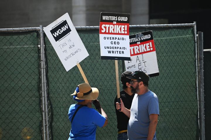 Hollywood writers on the picket line outside Universal Studios in Los Angeles on June 30. Around them are construction fences. The WGA and SAG-AFTRA have each filed grievances against NBCUniversal saying extensive construction at the studio has made conditions unsafe for picketers. 