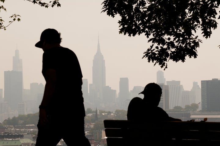 Haze caused by smoke from wildfires in Canada shrouds the New York City skyline as a man sits in a park on July 18 in Jersey City, New Jersey.