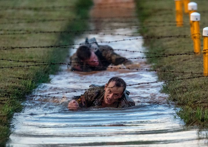 Competitors crawl underneath barbed wire strung across muddy water during the 2019 Best Ranger competition at Fort Benning in Georgia.