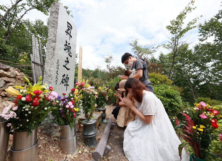 日航機墜落事故の現場にある「昇魂之碑」の前で手を合わせる遺族ら＝2022年8月12日、群馬県上野村
