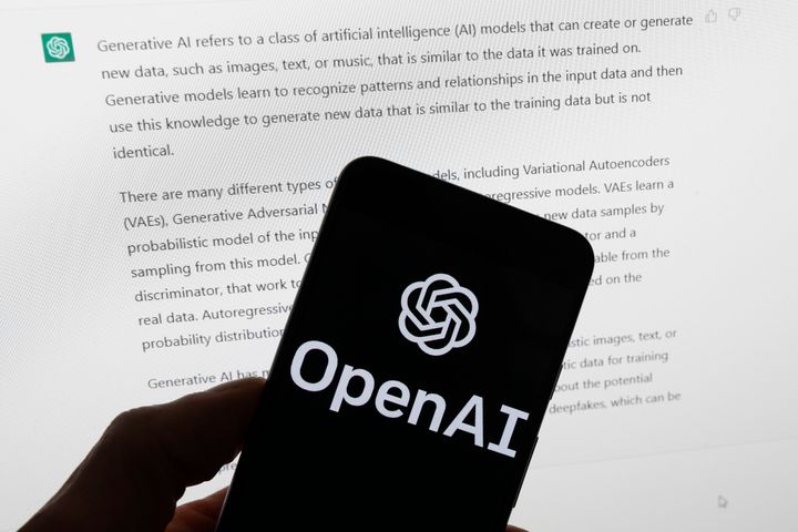 The OpenAI logo is seen on a mobile phone in front of a computer screen showing the output of ChatGPT, on March 21, 2023, in Boston.