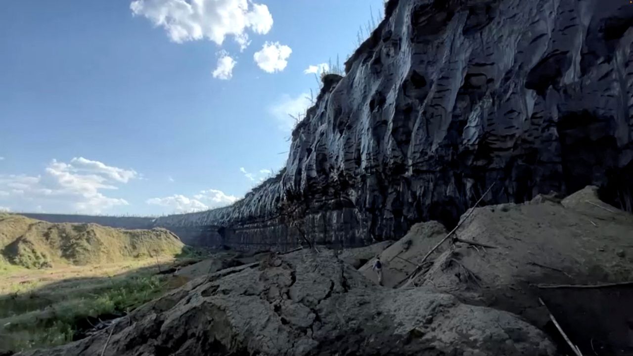 A person walks at the Batagaika crater, as permafrost thaws causing a megaslump in the eroding landscape, in Russia's Sakha Republic in this still image from video taken July 11 or 12, 2023. Reuters TV via REUTERS