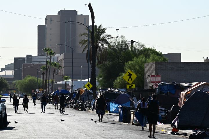People walk in the street in "The Zone," a vast homeless encampment where hundreds reside, during a record heat wave in Phoenix on July 19.