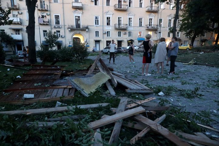 People stand among the debris outside a residential building after a missile strike in Odesa, early on July 23.