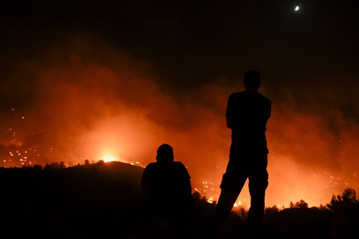 People watch the fires near the village of Malona in the Greek island of Rhodes on July 23, 2023.